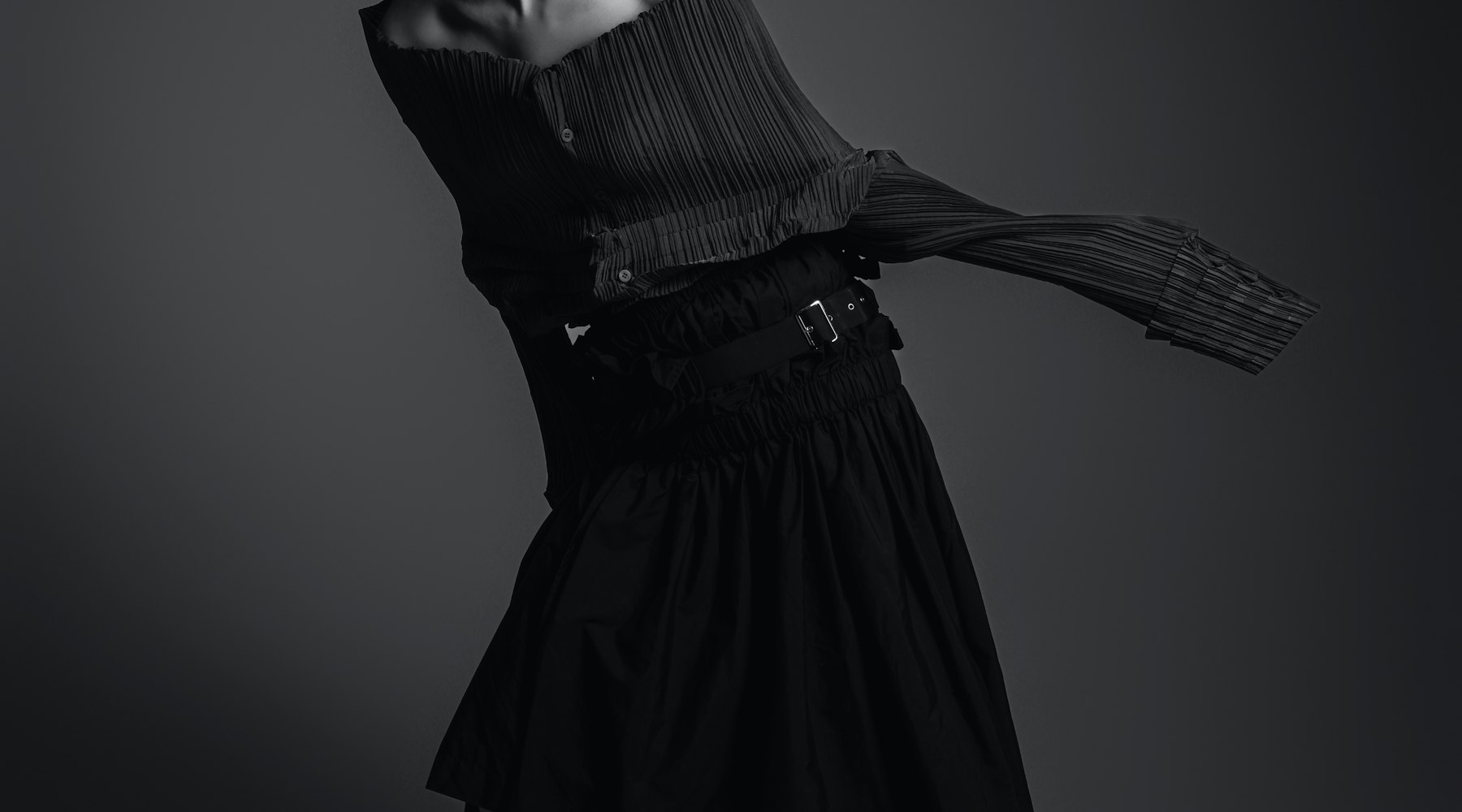 Black pleated garment with the face fully out of frame